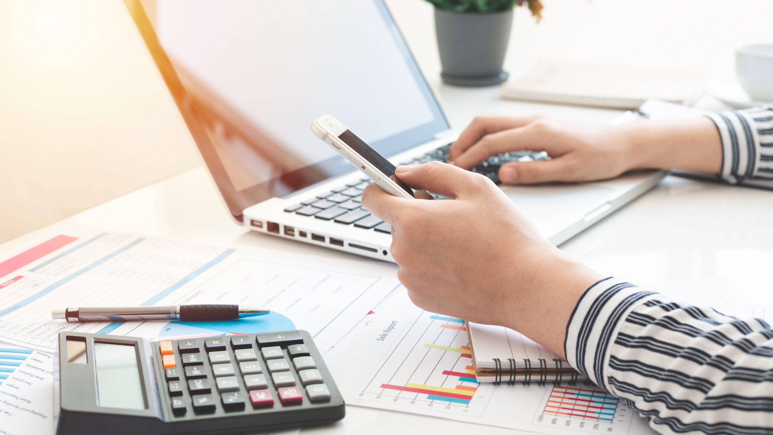 Business woman using calculator and writing make note with calculate. taxes and economic concepts. Savings, finances and economy concept through a laptop.